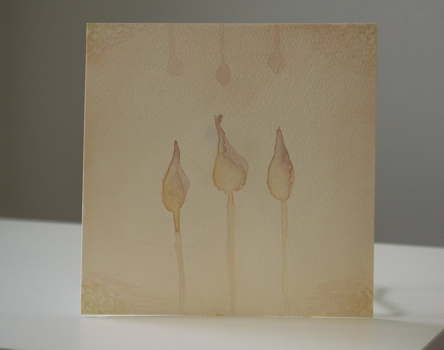 Beige card with watercolor illustrations of three abstract shapes on a plain background