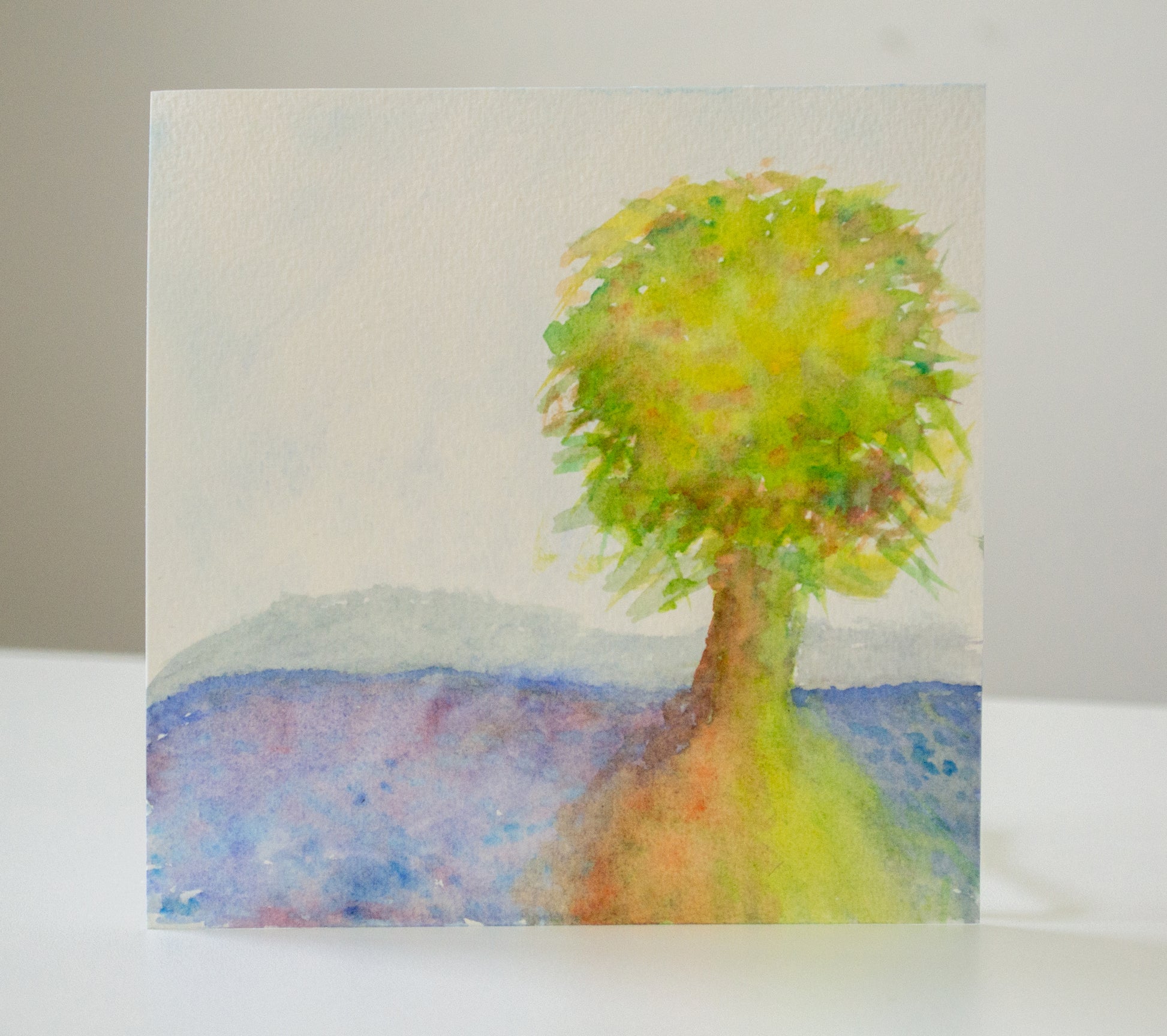 Artistic depiction of a tree with a colorful landscape in the background