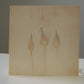 Beige card with watercolor illustrations of three abstract shapes on a plain background