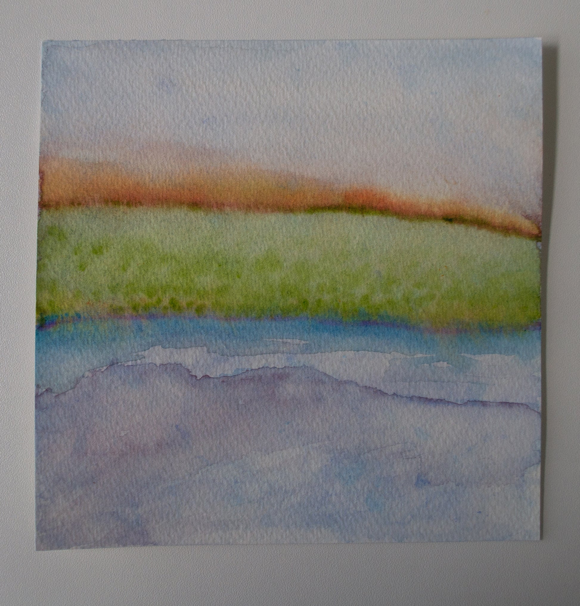 Watercolor painting of a landscape with green field and blue water on a gray background